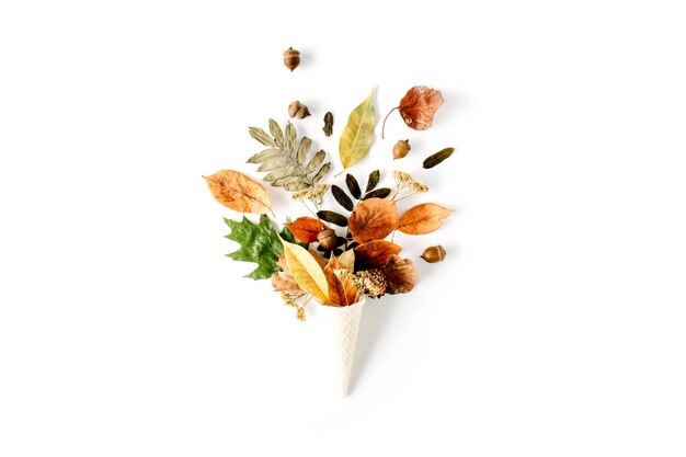 Waffle cone with dried autumn leaves bouquet on white