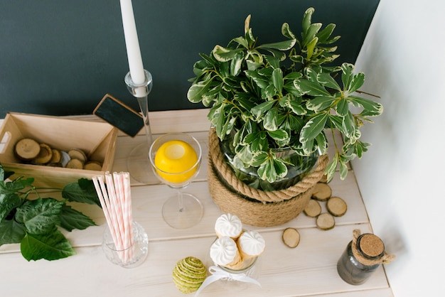 Waffle cone with white ice cream in a glass vase, paper tubes and a plant in a vase on the kitchen table or in a cafe, top view