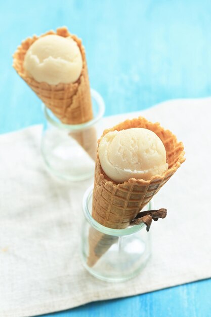 Waffle cones with delicious vanilla icecream in jars on table