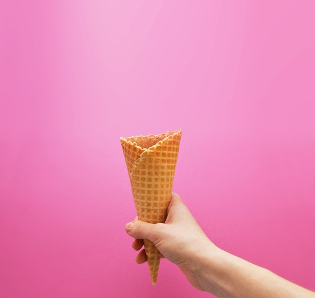 Waffle in hand on a bright pink background