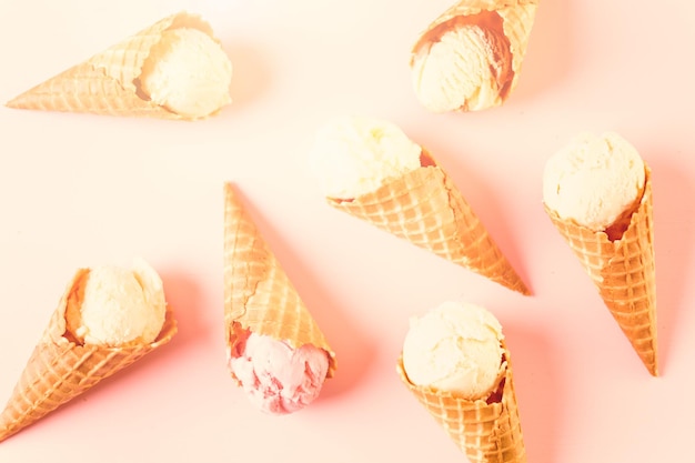 Waffle ice cream cones with plate of ice cream scoops on a pink background.