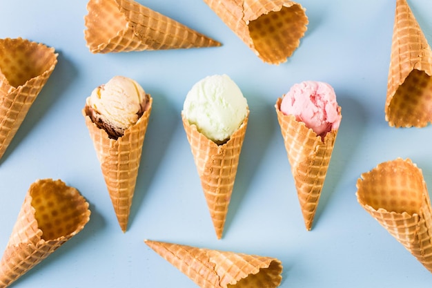 Waffle ice cream cones with scoops of ice cream on a blue background.