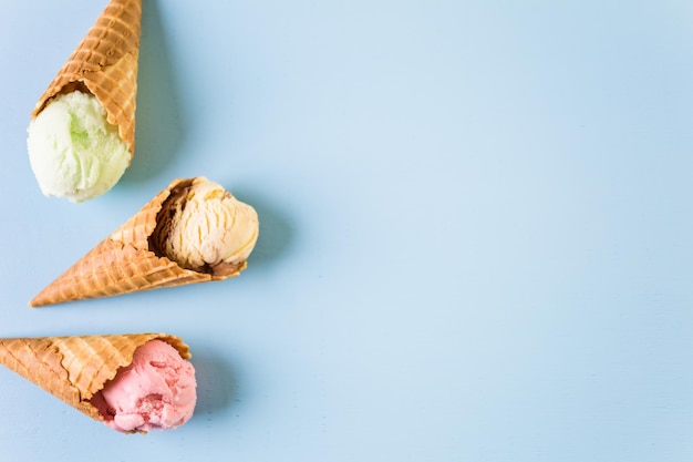 Waffle ice cream cones with scoops of ice cream on a blue background.