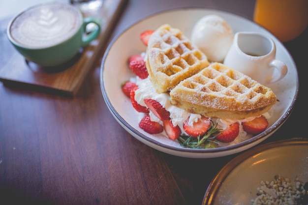 Waffle pancake desert with vanilla ice cream fresh strawberry and honey syrup