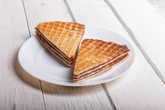 Waffle sandwiches with boiled condensed milk in plate on white wooden table 