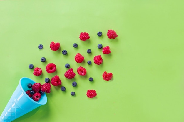 Waffle sweet ice cream cone with raspberries over white wooden background top view Flat layCreative food concept with colorful cone on pastel background Mix of summer berries