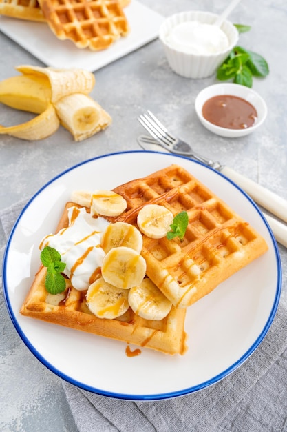 Waffles with banana whipped cream and salty caramel on a gray concrete background