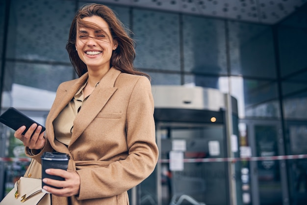 Waist-up portrait of a lovely modern young Caucasian woman with her eyes closed laughing heartily