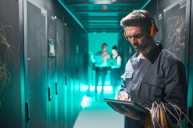 Waist up portrait of network engineer using tablet in server room during maintenance work in data center, copy space