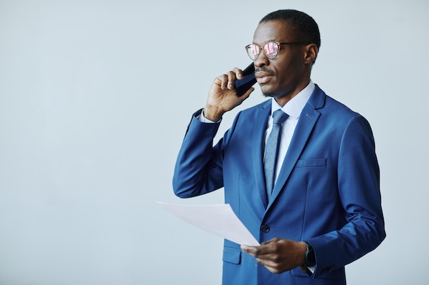 Waist up portrait of professional african american businessman speaking on phone in office copy space