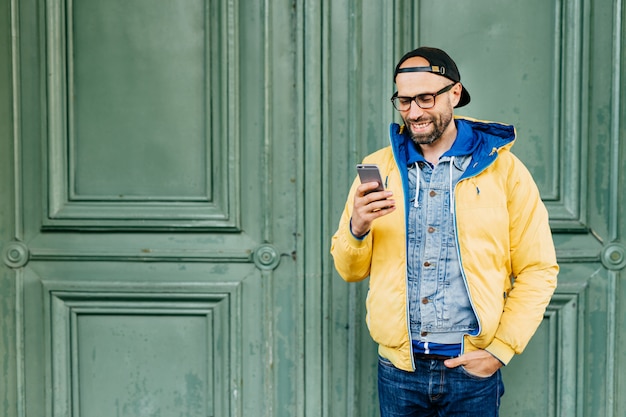 Waist up portrait of trendy hipster with beard dressed in casual clothes holding hand