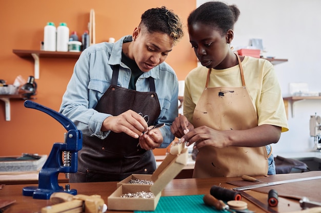 Waist up portrait of two female artisans in leatherworking shop creating handmade pieces together