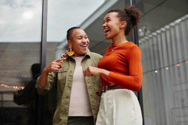 Waist up portrait of two young women laughing carefree white enjoying outdoor party at rooftop