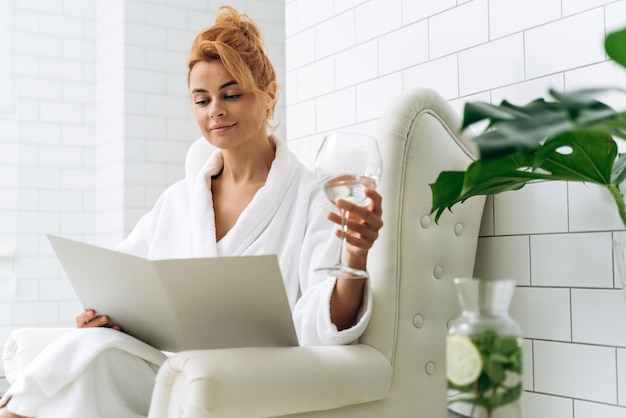 Waist up portrait view of the caucasian woman reading clients agreement while sitting at the armchair at the cosmetology clinic