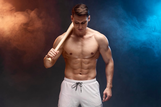 Waist up portrait view of muscle man posing in studio with baseball bat