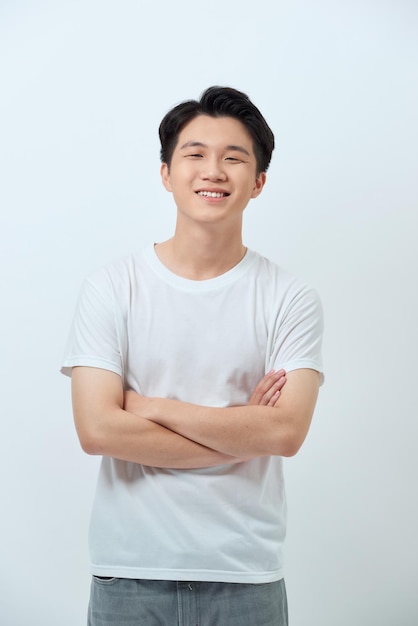 Waistup portrait of confident Asian man standing against white wall with arms crossed