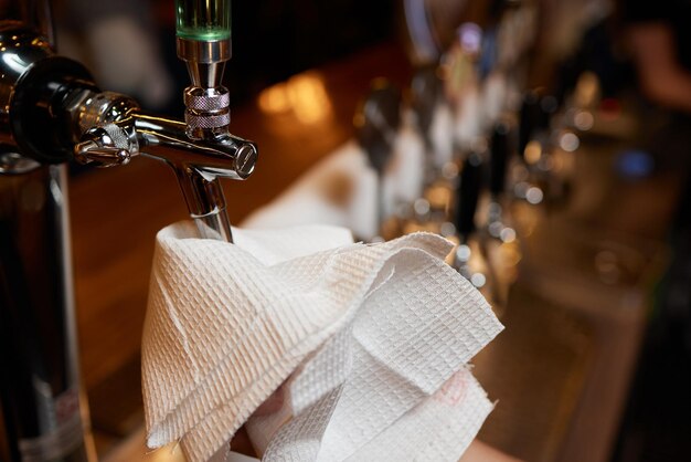 Waiter or bartender cleaning beer taps on the counter in pub and restaurant