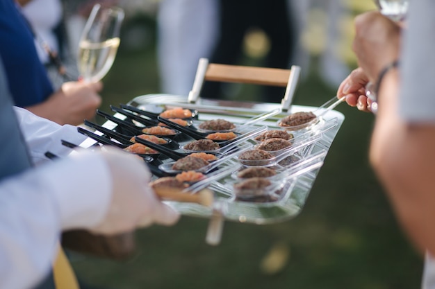 Waiter bring portioned salmon and beef tartare on a tray