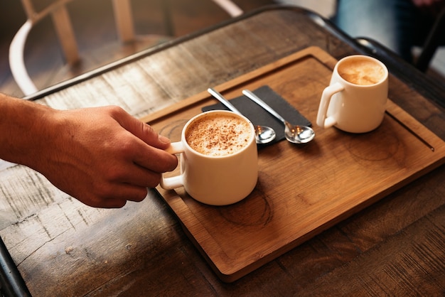 Waiter holding a tray with coffees in the bar.