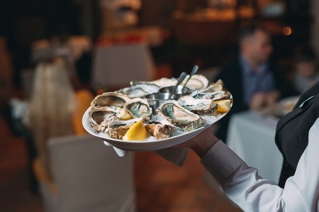 A waiter holds a serving of oysters in a restaurant