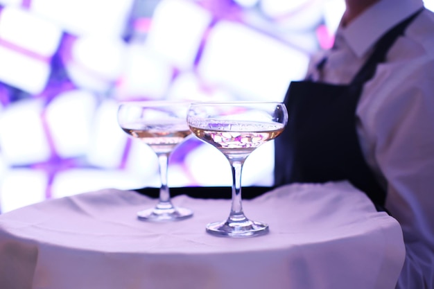 The waiter is holding a tray with two glasses of champagne Catering for the event