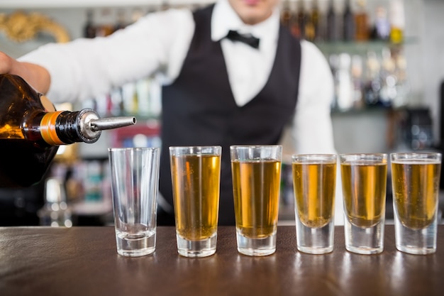 Waiter making shots at bar counter