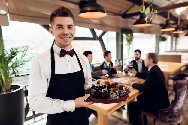 Waiter making tea for asian businessmen