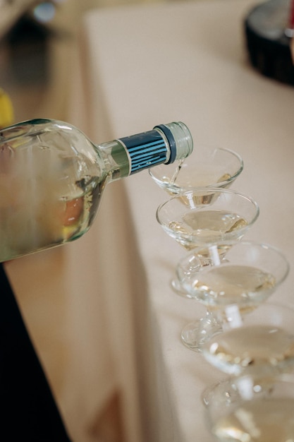 Waiter pouring martini or champagne in crystal glasses on table party at wedding reception