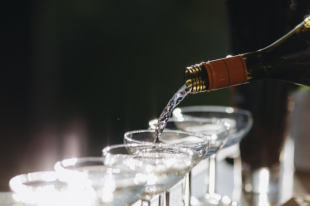 The waiter pours champagne in glasses on the street wedding catering look from below