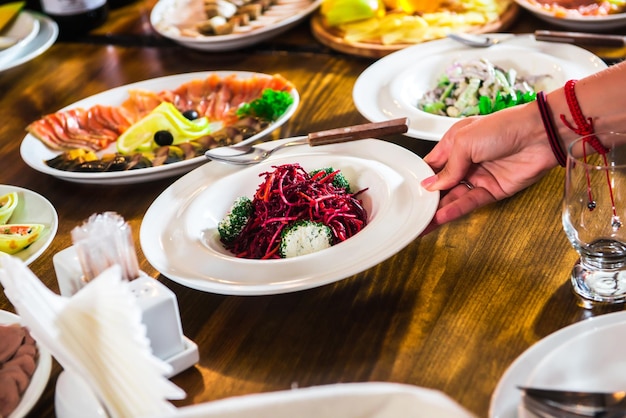 The waiter puts a salad on a table with different dishes