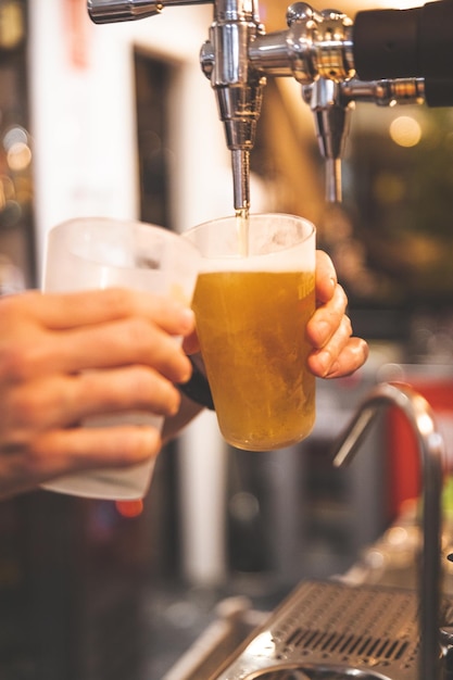 Waiter serving beer in a glass with a beer shooter.