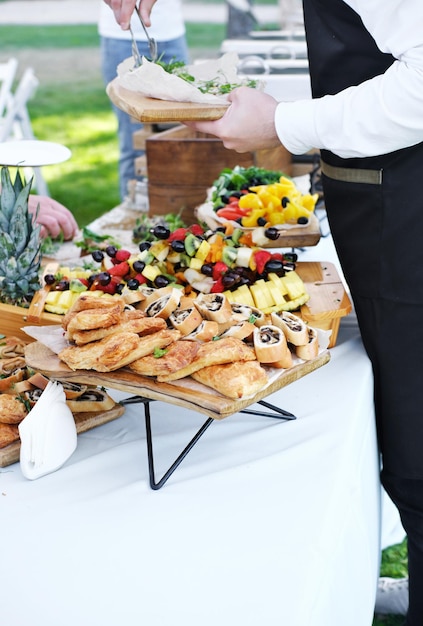 Waiter serving food to guests Catering service Wedding welcome food Fruits on skewers and canapes Welcome buffet at wedding reception