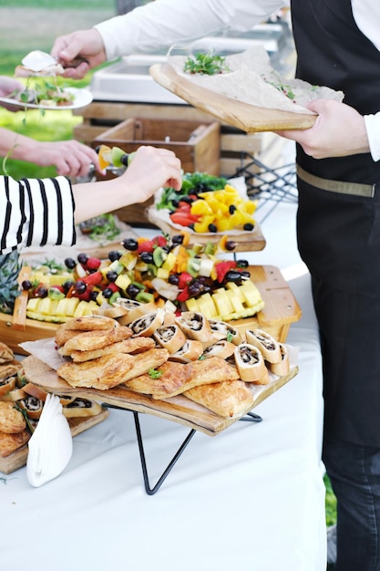 Waiter serving food to guests Catering service Wedding welcome food Fruits on skewers and canapes Welcome buffet at wedding reception