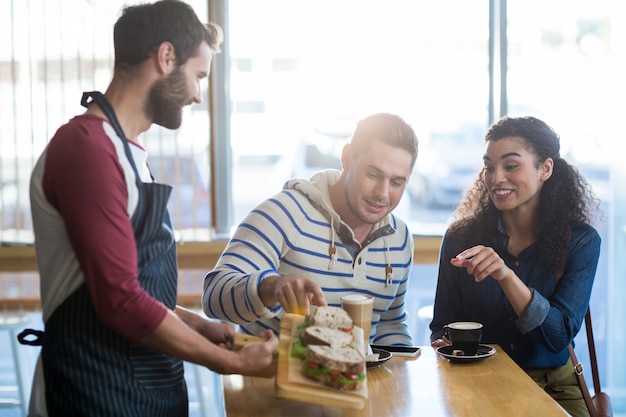 Waiter serving a plate of sandwich to customer