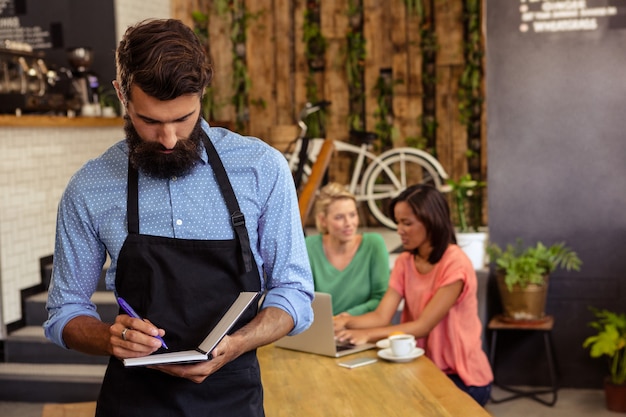 Waiter taking order in his book