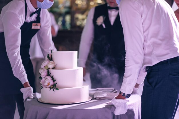 The waiter wine the newlyweds a wedding cake decorated with peonies