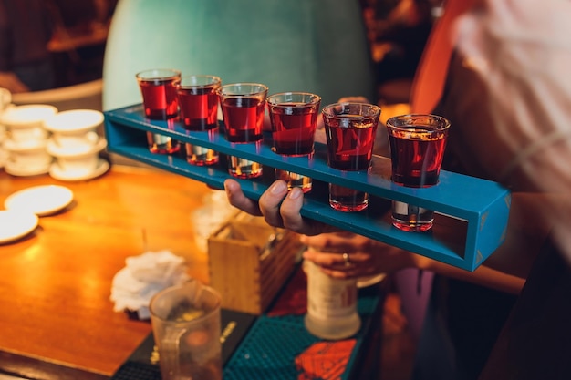 Waiter with tray takes empty beer glasses and brings cocktails to the guests of restaurant on the summer terrace Service in cafes and restaurants Man holding the tray with red cocktails