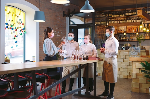 The waiters of the restaurant in a medical mask learns to distinguish between the glasses