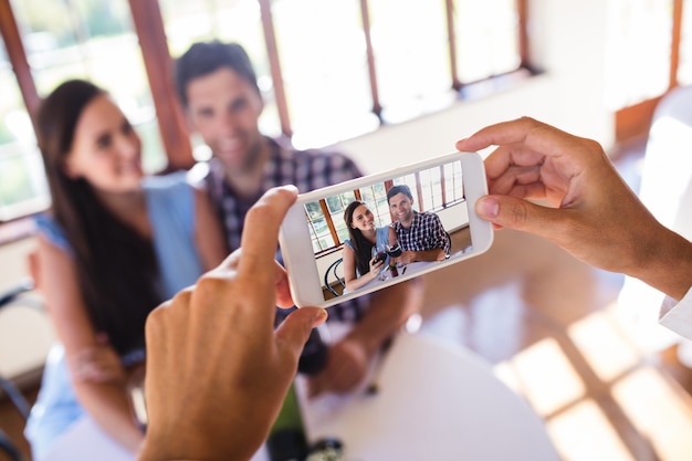 Waitress clicking photo of a couple in restaurant