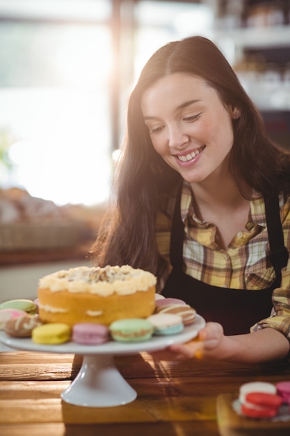 Waitress holding dessert on cake stand in cafe