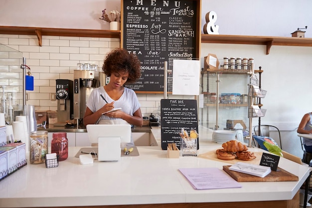 Waitress writing down an order at the counter of coffee shop