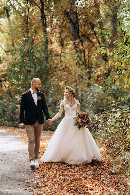 Walk of the bride and groom through the autumn forest