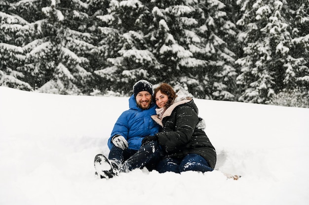 Walk in winter. Embracing couple enjoying snowfall. Man and woman having fun in the frosty forest. Romantic date in winter time.Christmas mood of a young family.  Love and leisure concept