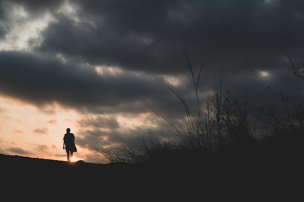 Walking alone on a hill with sunset in background