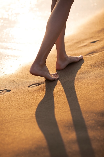 Walking barefoot along the surf on the sand beach at sunset