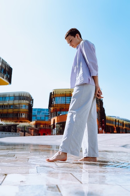 Walking barefoot on water, on puddle on street tiles, on blurred background of urban architecture