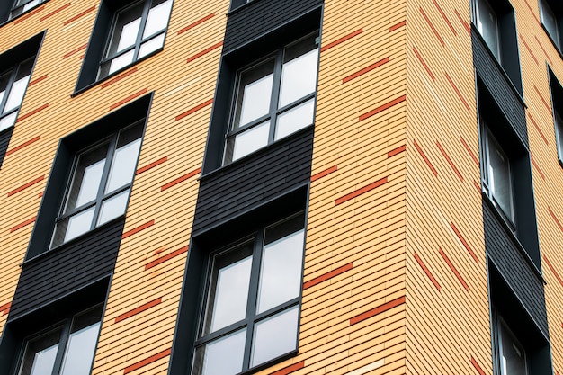 The wall of a brick multistoried building with transparent windows. Geometric abstract pattern. House facade texture, background.