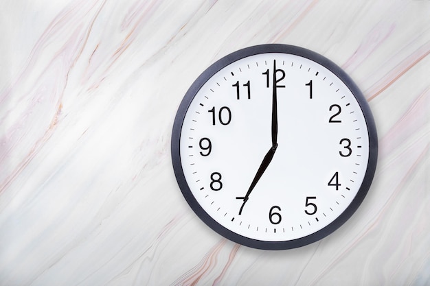 Wall clock show seven o'clock on marble texture Office clock show 7pm or 7am