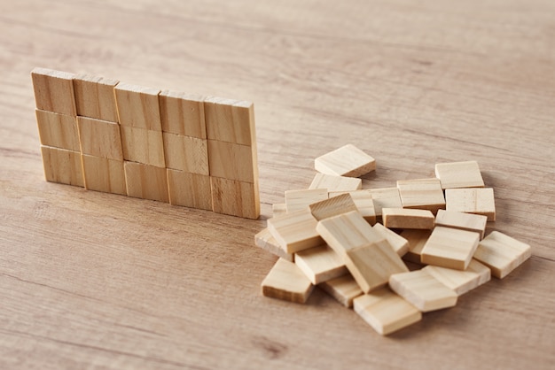 Wall made of wooden blocks on wood table. Finishing task concept