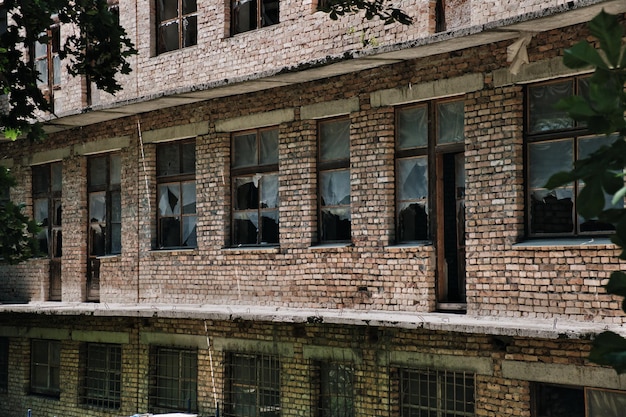 The wall of an old abandoned brick building with broken windows